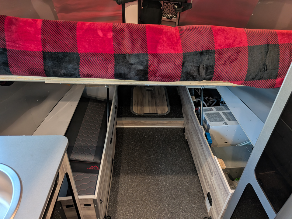 Custom king bed lifted on struts — under-bed storage and electrical bay