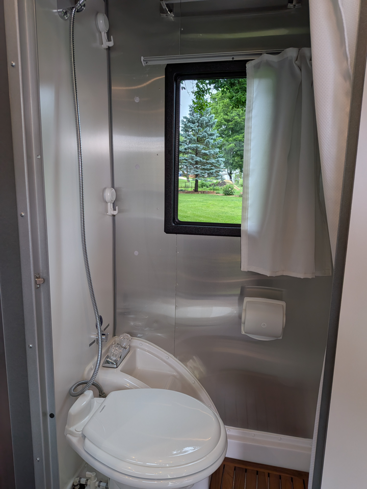 Wet bath with teak floor, shower, and window